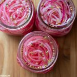 Three glass jars filled with quick pickled red onions