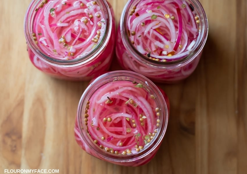 Three glass jars filled with quick pickled red onions