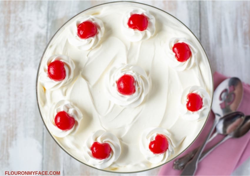 Overhead photo of the top of Pink Salad recipe showing a ring of whipped cream flowers with a maraschino cherry in each center