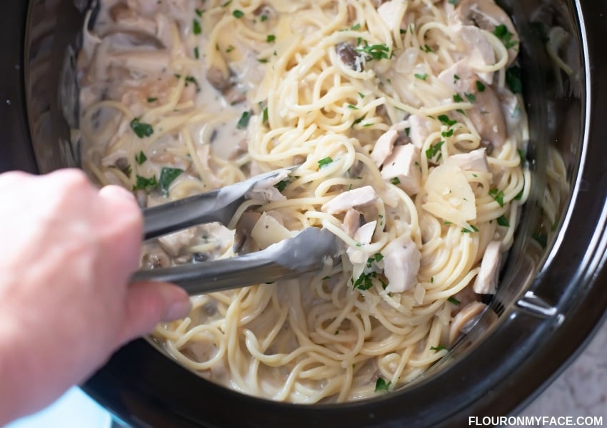 Crock Pot filled with cooked chicken Tetrazzin with pasta.