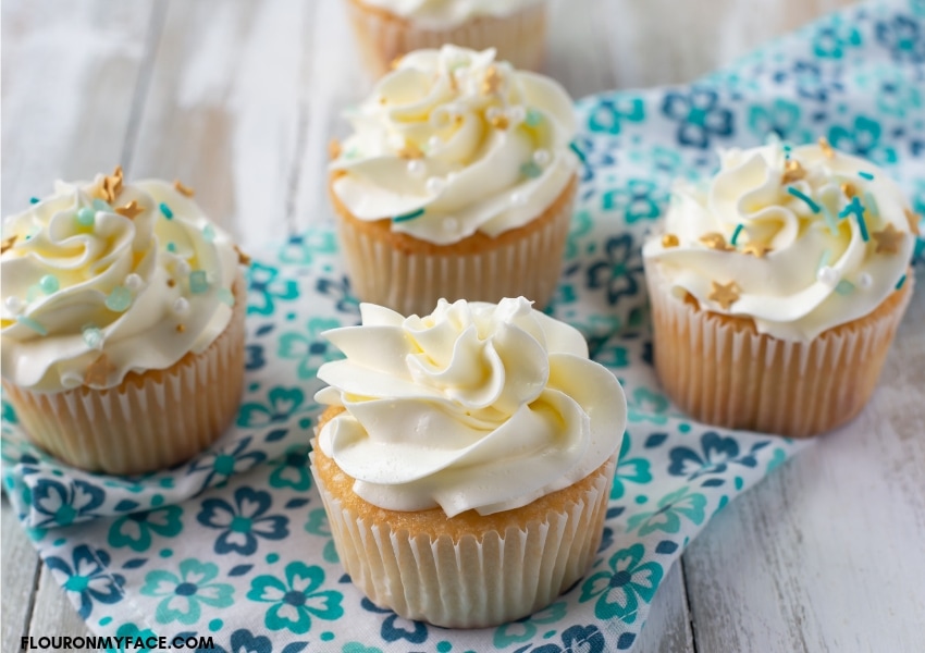 4 homemade vanilla cupcakes frosted with homemade Swiss meringue buttercream frosting with sprinkles.