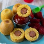 A blue plate with Instant Pot Corn Dog Bites and fresh sliced strawberries.
