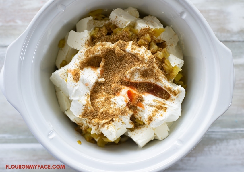 Overhead view of a 2.5 quart crock pot filled with the ingredients to make hot white Queso dip