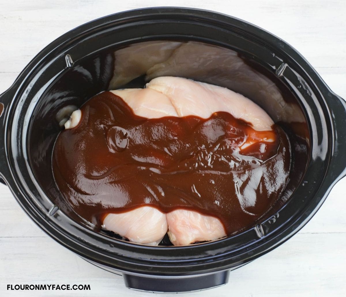 Chicken with barbecue sauce inside a slow cooker.
