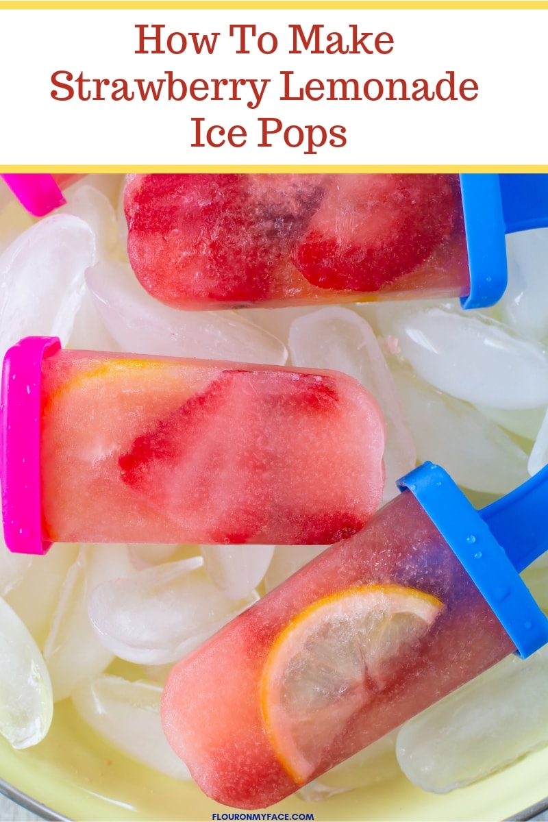 close up photo of homemade Strawberry Lemonade Ice Pops in a yellow granite-ware pan nestled on a bed of ice cubes..