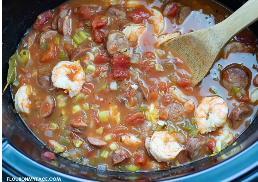 over head view of a crock pot filled with Shrimp and sausage jambalaya ingredients before cooking