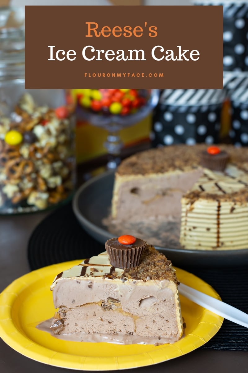 A slice of Reese's Ice Cream Cake from Carvel on a paper plate with the cut ice cream cake in the background on a party tables decorated for a Reese's themed birthday party.