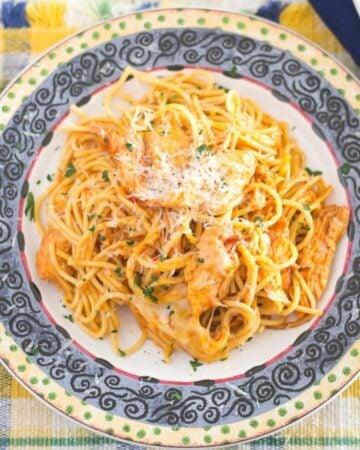 A dinner plate with a large serving of Chicken spaghetti topped with melted cheese.