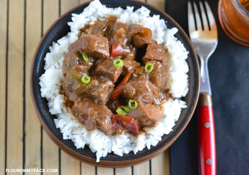 a serving bowl filled with rice and pepper steak.