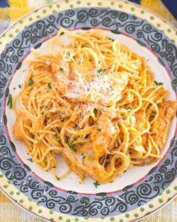 A dinner plate with a large serving of Chicken spaghetti topped with melted cheese.