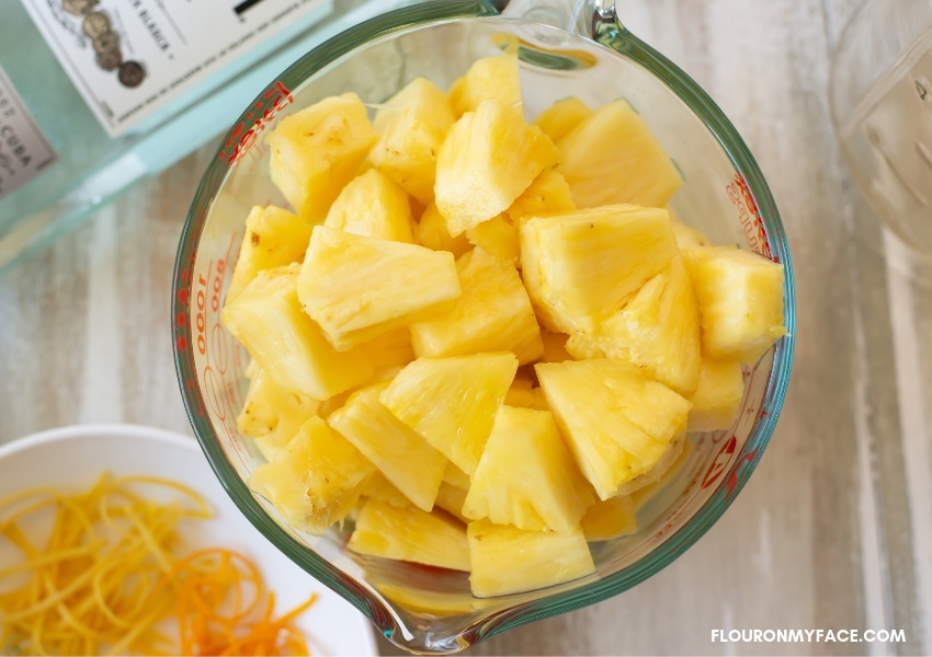 a glass measuring cup filled with fresh pineapple that has been cut into chunks