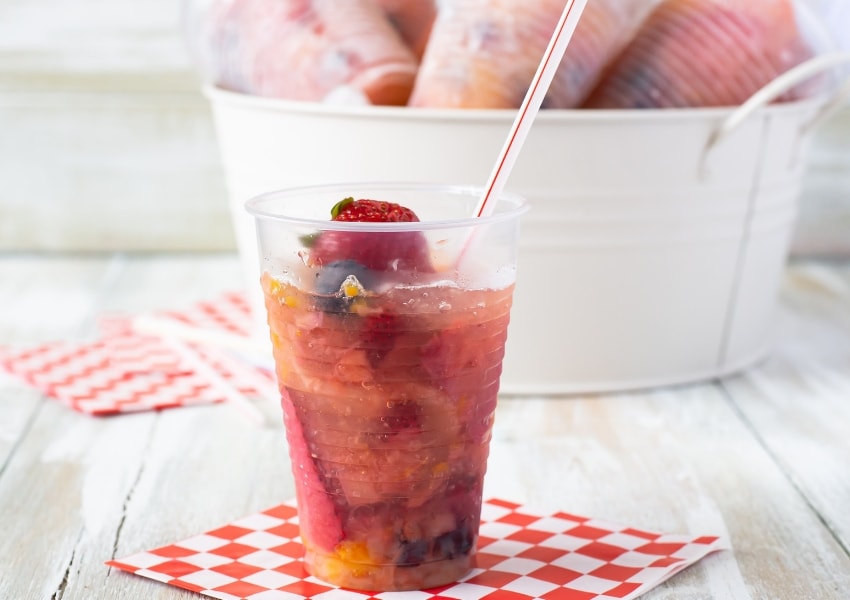 Individual Frozen Fruit Cups for the 4th of July. A frozen fruit treat served with a straw and a spoon.