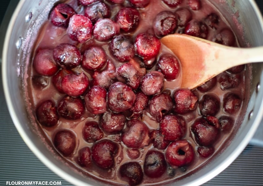 Fresh pitted cherries in a pot that have been boiled with sugar until glossy for homemade small batch cherry preserves