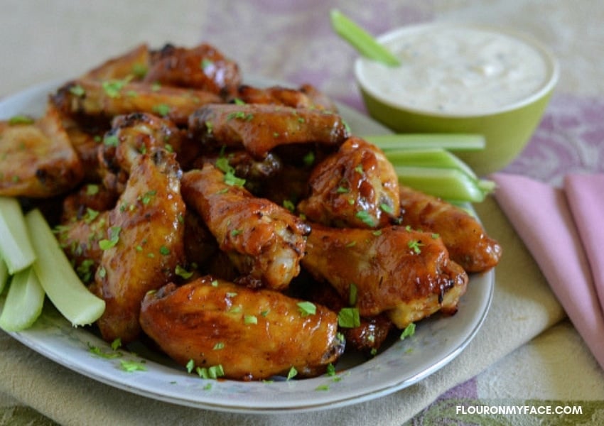 A serving platter piled high with Honey BBQ Chicken Wings. Celery sticks on the side with a dish of ranch dressing dipping sauce.