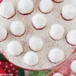 Freshly baked Mexican Wedding Cookies arranged on a red cake stand with powdered sugar sprinkled over the top.