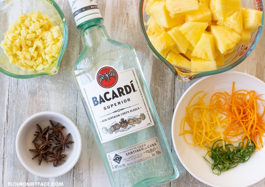 Pineapple ginger rum ingredients in individual bowls with a bottle of Bacardi white rum.