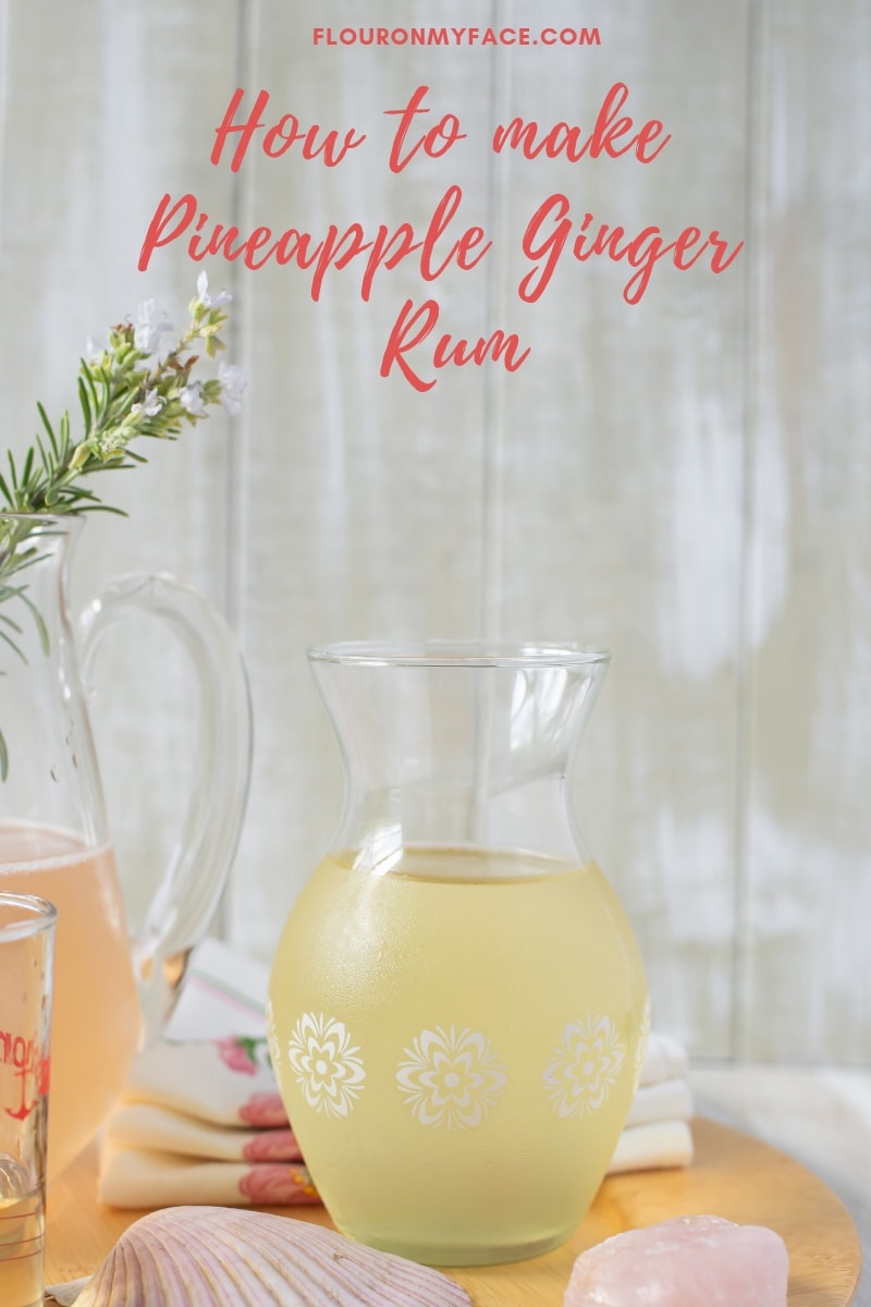 A decanter with homemade Pineapple Ginger Rum with the ingredients to make a Shell Beach Cocktail recipe 