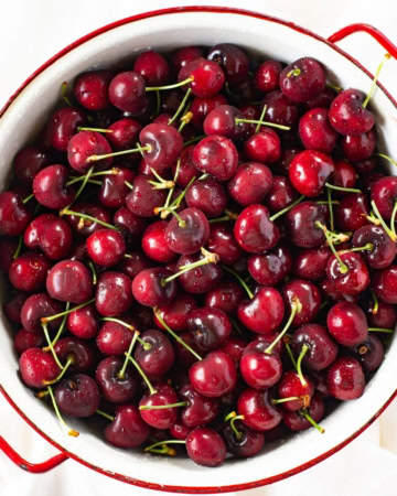 A colander filled with fresh sweet cherries.