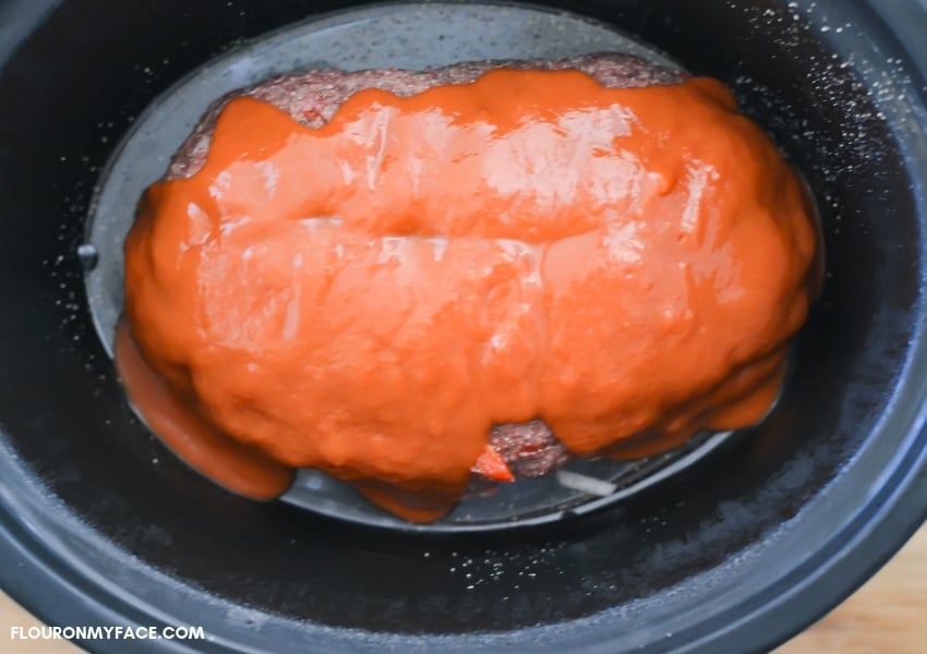 A meatloaf with tomato soup poured over it in the crock pot before cooking