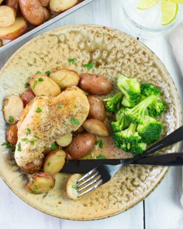 A dinner plate with a serving of crock pot chicken and potatoes with a side of steamed broccoli.