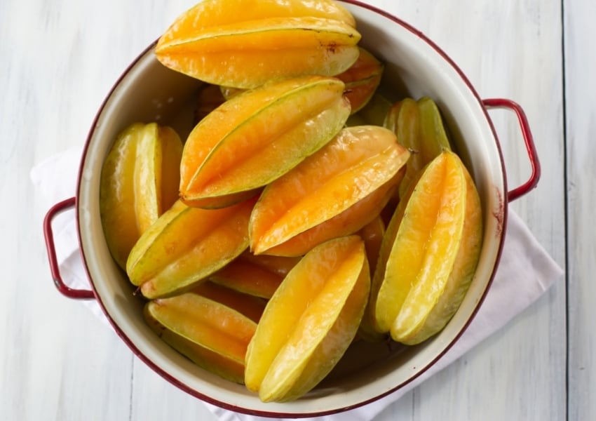 a white enamel strainer filled to overflowing with fresh carambola fruit.