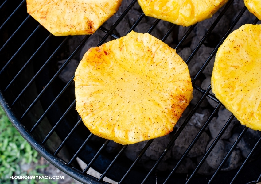 Whole pineapple slices on a charcoal grill