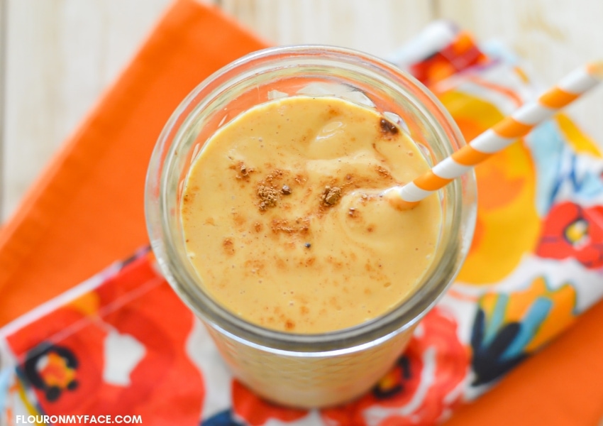 over head photo of a glass filled with a Pumpkin Spice Smoothie on top of a fall colored cloth napkin 