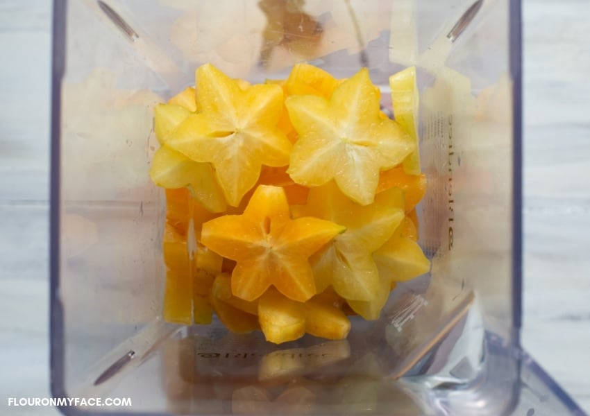 Overhead photo of a blender filled half way with sliced carambola fruit