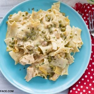 Overhead photo of a blue glass plate with a serving of Chicken Noodle Casserole piled high, with a red and white polka dot cloth napkin in the background.