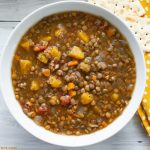 overhead photo of a white glass bowl filled with a serving of Lentil and Butternut Squash Soup