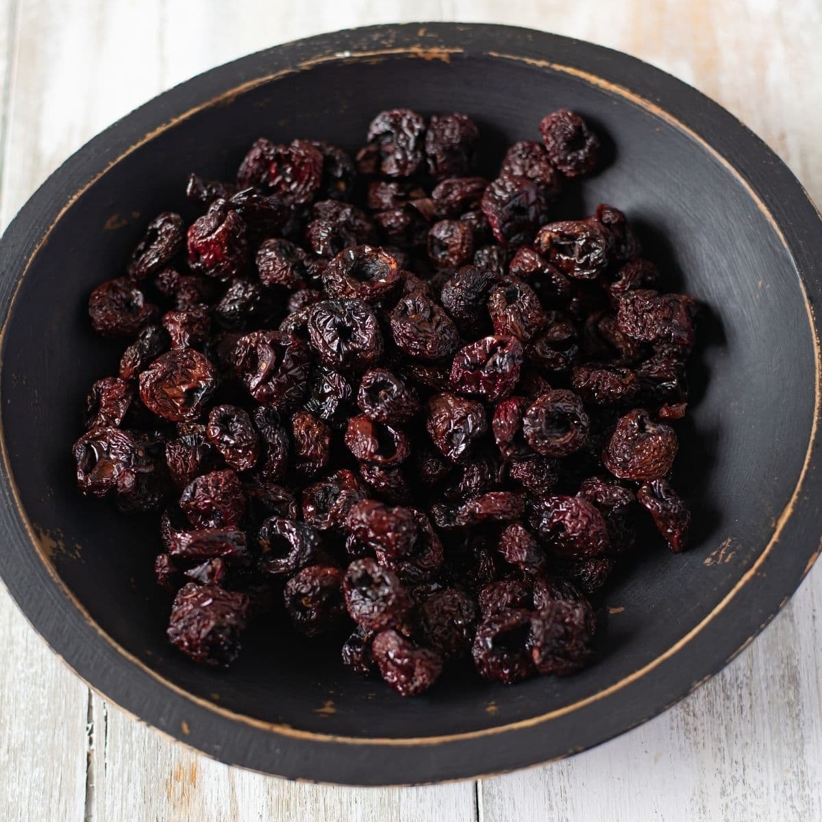 Dehydrated Cherries in a black wooden bowl.