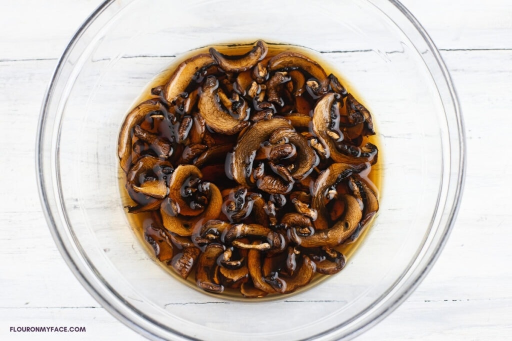 Rehydrated dried mushrooms in a bowl soaking in the mushroom broth