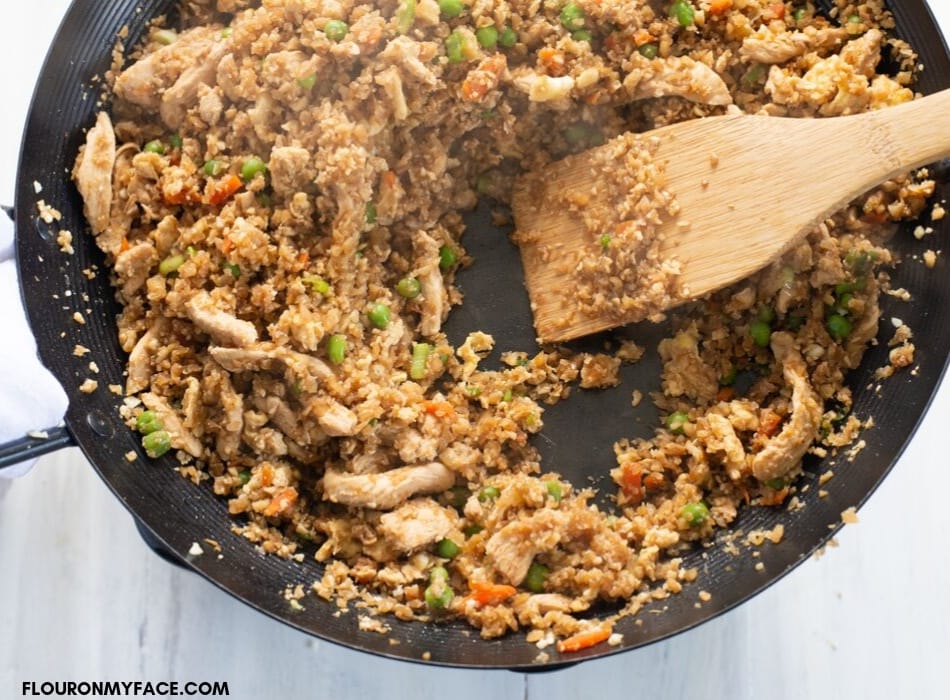over head photo of a skillet filled with stir fried chicken cauliflower rice
