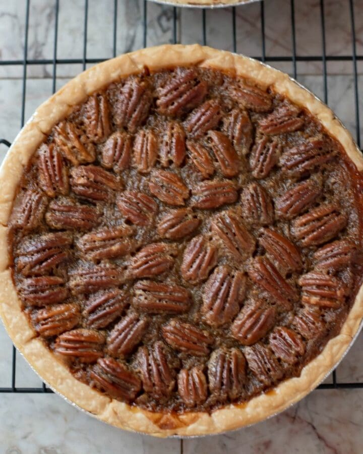 A homemade pecan pie on a wire rack cooling.