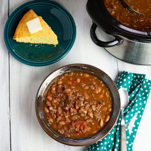 Crock Pot Cowboy Bean Soup in a bowl with a piece of cornbread in the background.