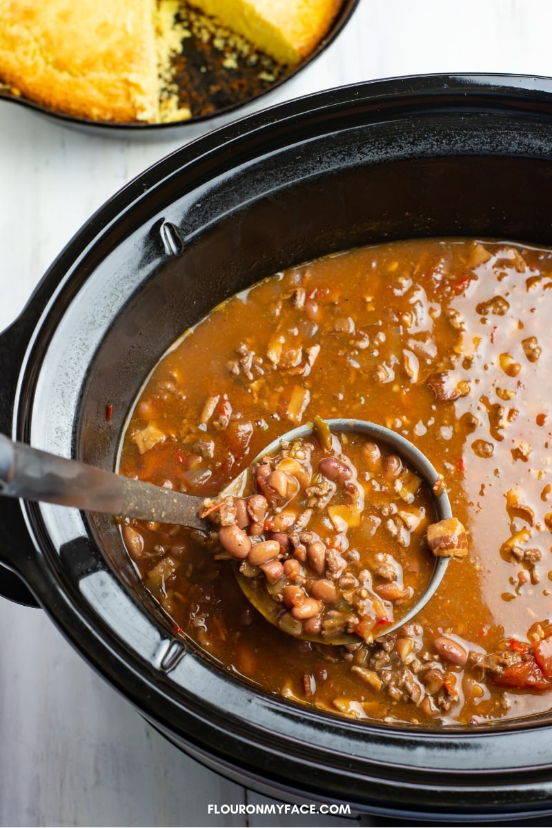 Image of a ladle scooping a helping of Crock Pot Cowboy Bean Soup up to fill a bowl