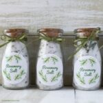 The mini bottles with a cork filled with rosemary salt, labels and tied with a green ribbon at the top.