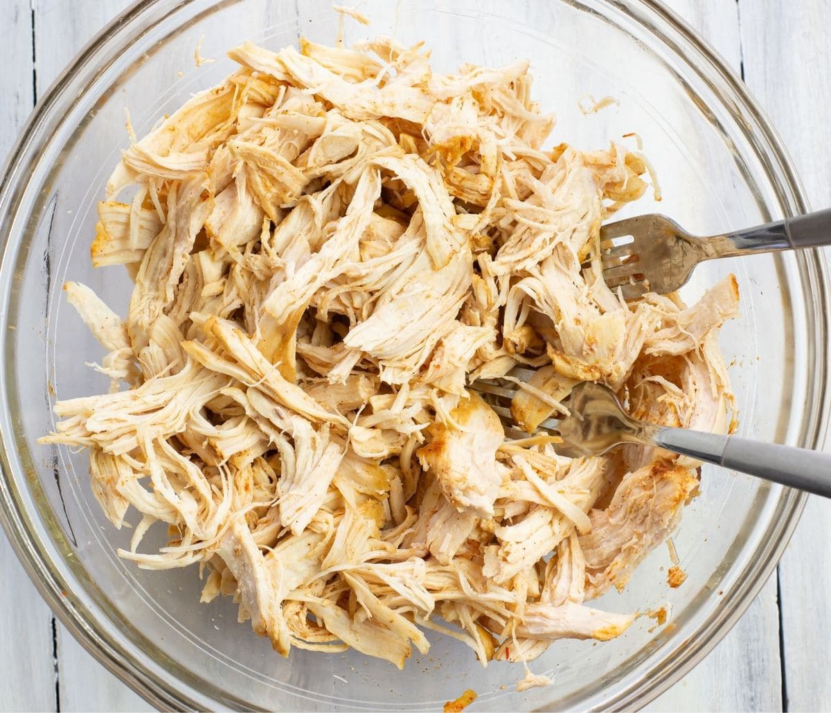 a glass bowl filled with shredded chicken.