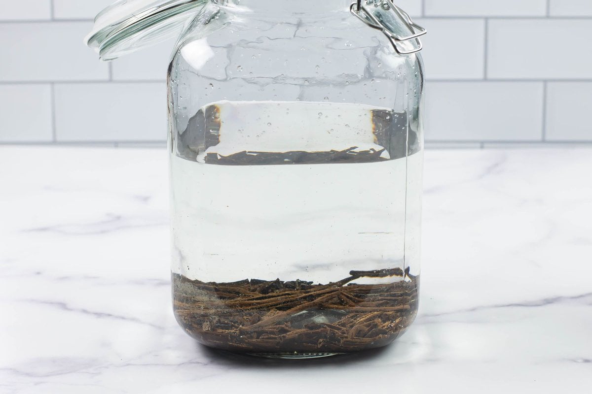 A glass jar filled with vodka and vanilla bean pods.