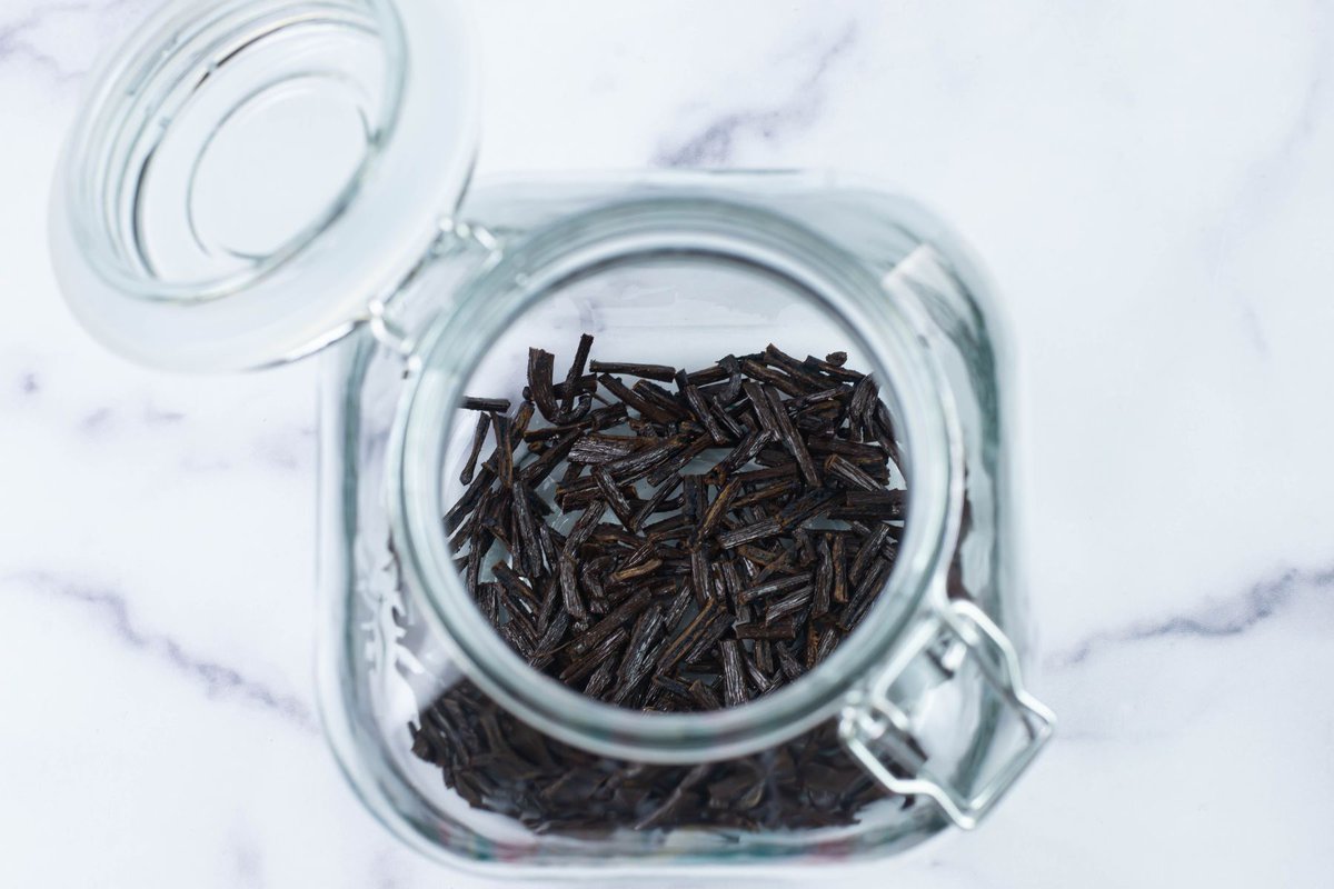 Vanilla beans in the bottom of a large glass jar.