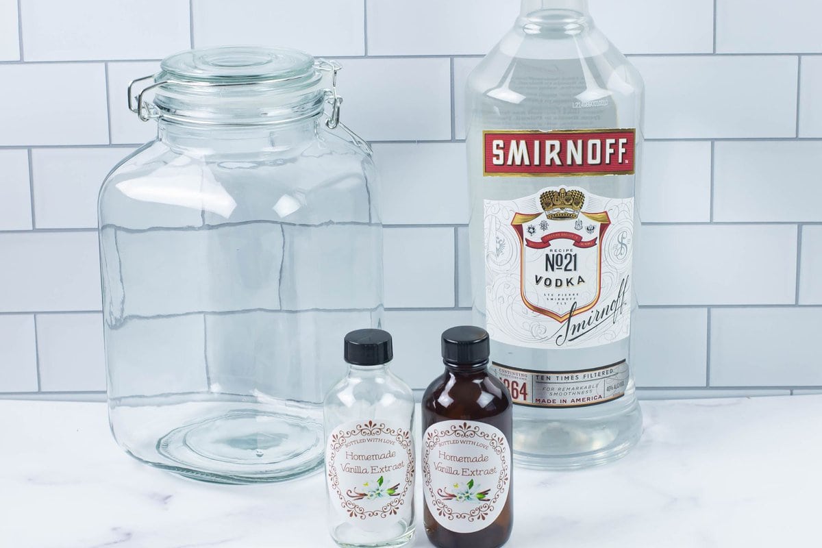 A large glass jar, a bottle of vodka and small jars to use to make homemade vanilla extract.