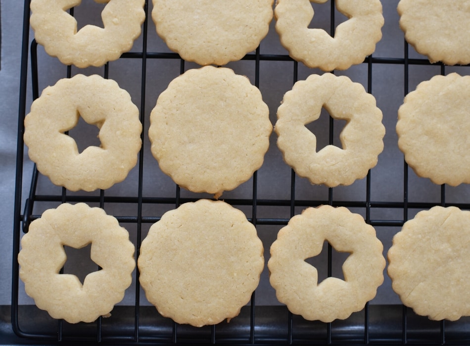 Freshly baked raspberry Linzer Cookies cooling before filling with raspberry jam