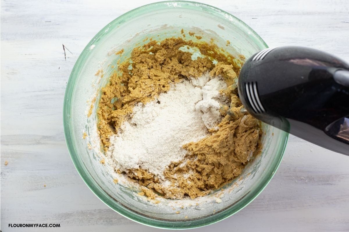 Beating flour into cookie dough with a mixer.