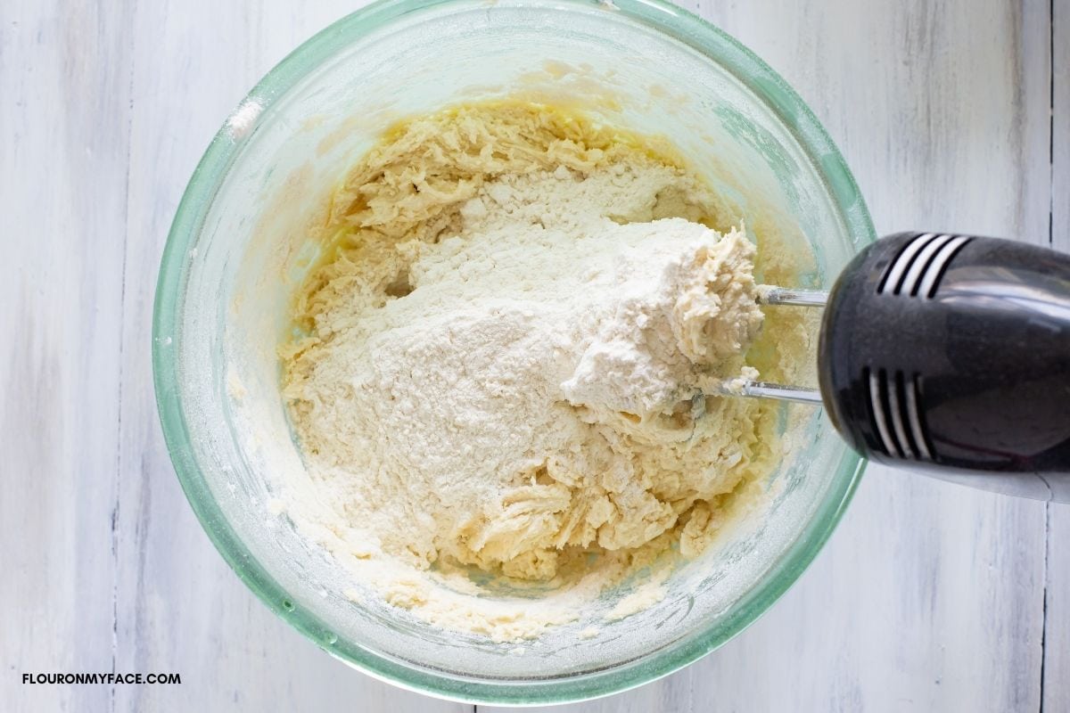 Adding flour to the bowl of cookie dough.