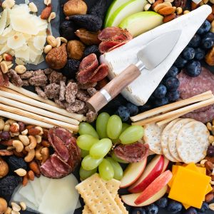 Overhead closeup photo of a holiday cheese platter with cheese, meats, crackers and nuts