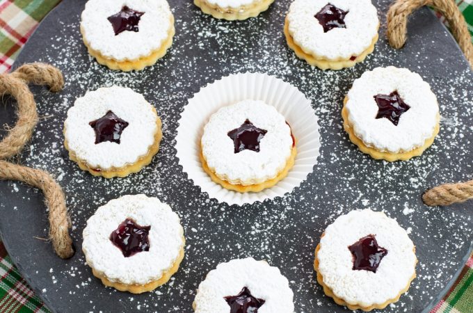 Raspberry Linzer Sandwich Cookies on a slate serving platter