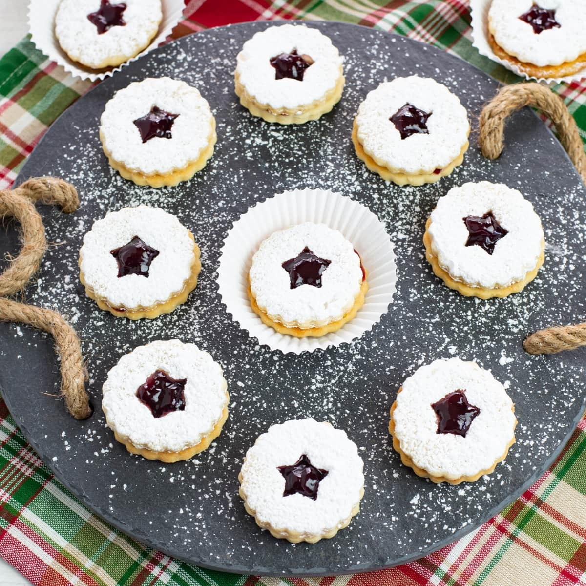 Raspberry Linzer Sandwich Cookies on a slate serving platter