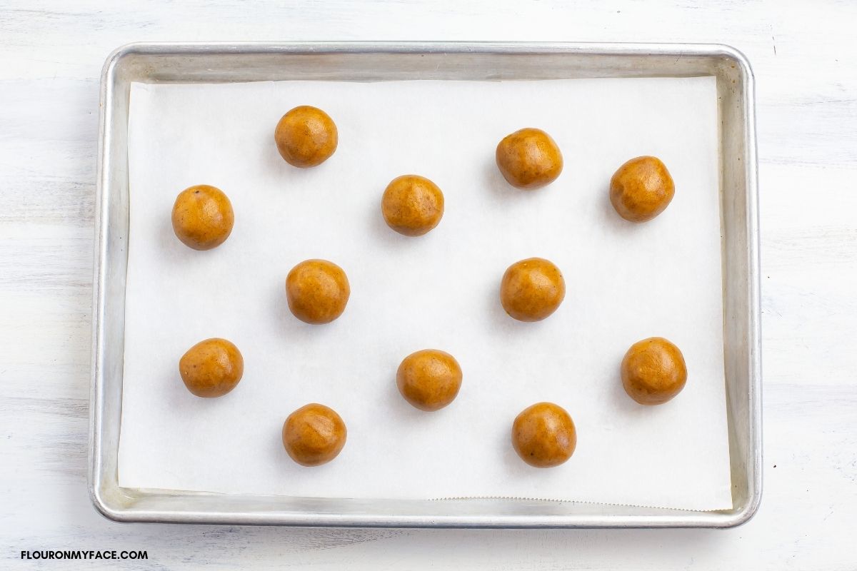 Rolled cookie dough balls on a baking sheet.