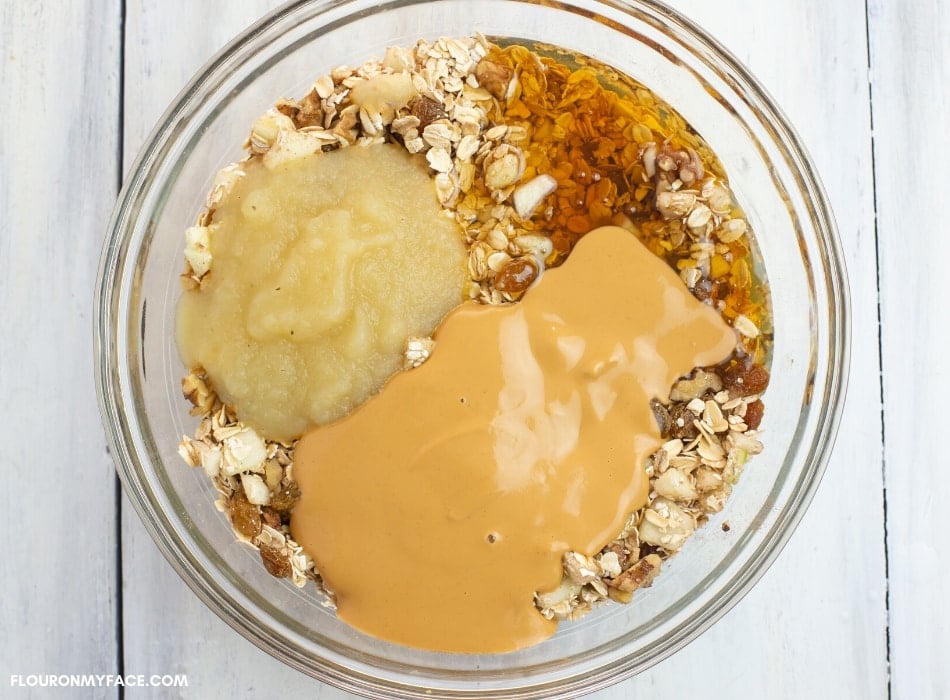 A mixing bowl with oatmeal, peanut butter, apple sauce and honey before mixing