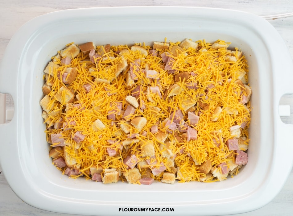 Overhead photo of a casserole crock pot filled with the ingredients to make a ham and egg breakfast casserole